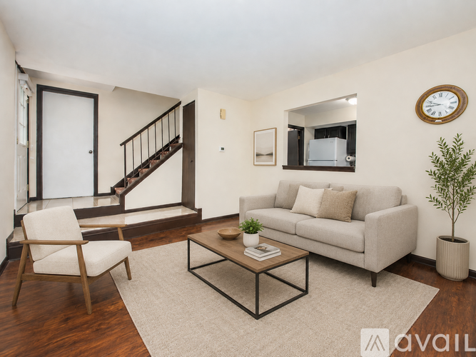 A living room with a white couch, a wooden chair, a coffee table, and a plant.