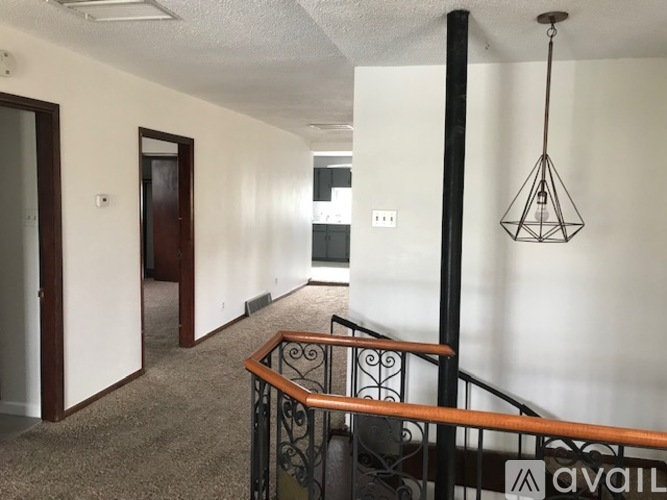 A hallway with a black railing and a light hanging from the ceiling.