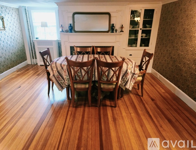 A dining room with a wooden floor and a fireplace.