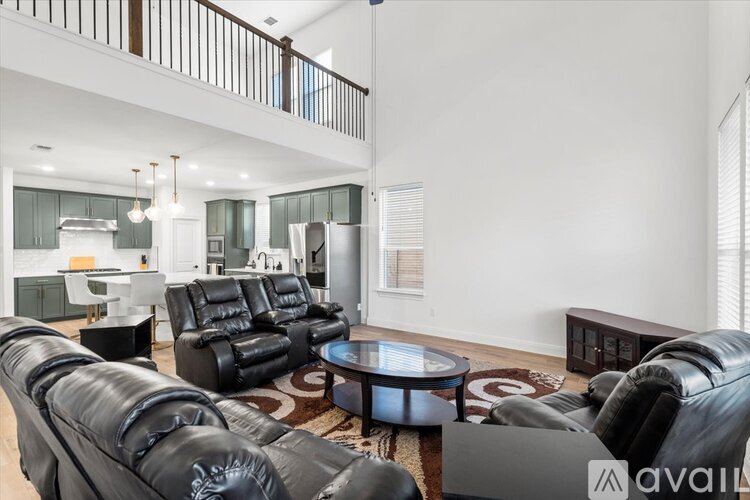 A living room with black leather furniture and a glass coffee table.