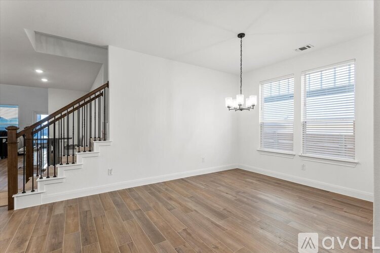 A spacious room with wooden floors and a chandelier hanging from the ceiling.