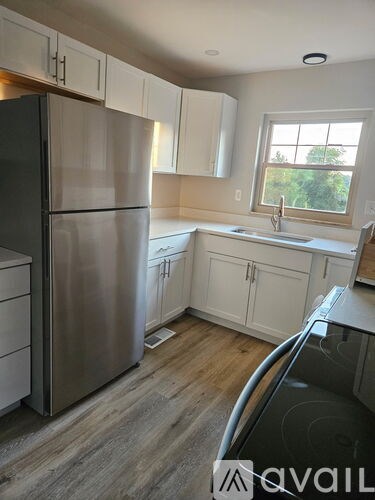 A kitchen with a stainless steel refrigerator and white cabinets.