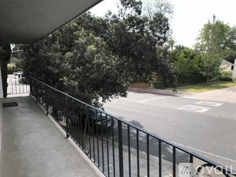 A balcony with a black railing overlooks a street.