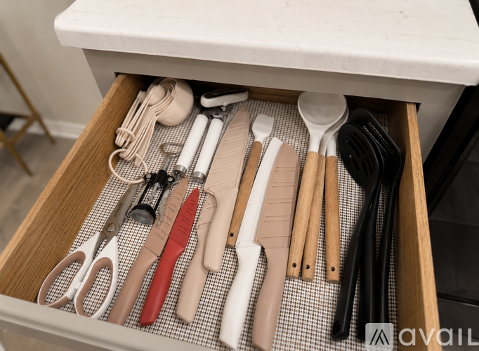 A drawer full of kitchen utensils including scissors, knives, and spoons.