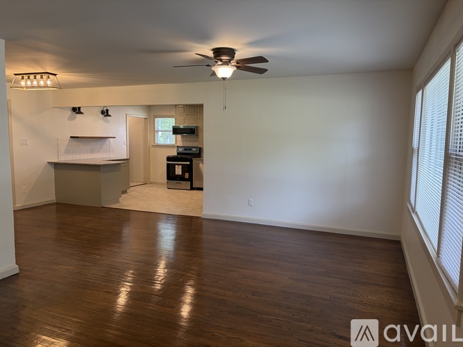 A spacious room with wooden flooring and a ceiling fan.