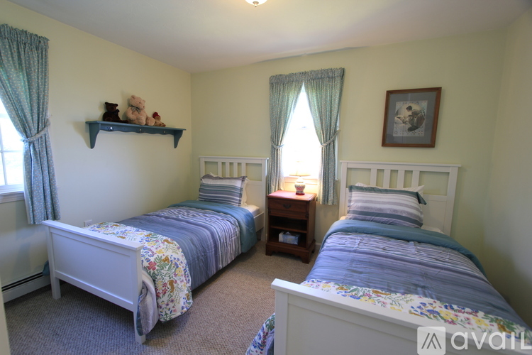 A bedroom with two beds and a teddy bear on the shelf.