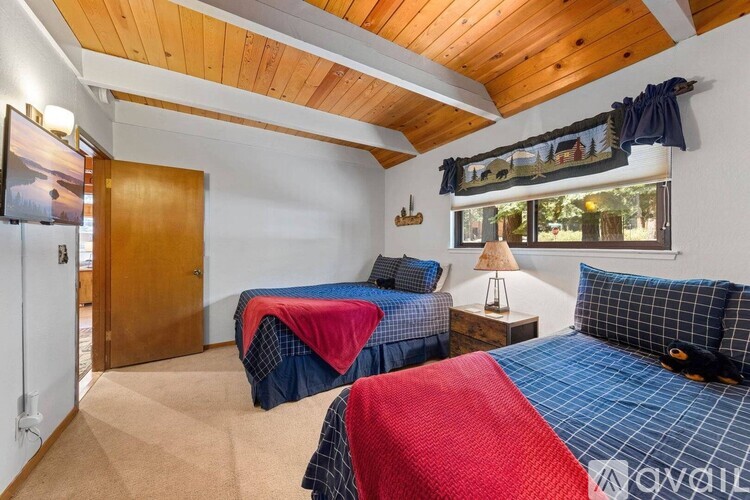A bedroom with two beds and a wooden ceiling.