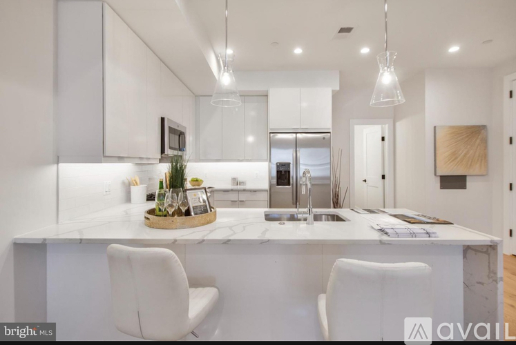 A modern kitchen with white cabinets and a marble island.