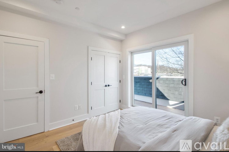 A bedroom with a large bed and a view of the backyard through the sliding glass door.