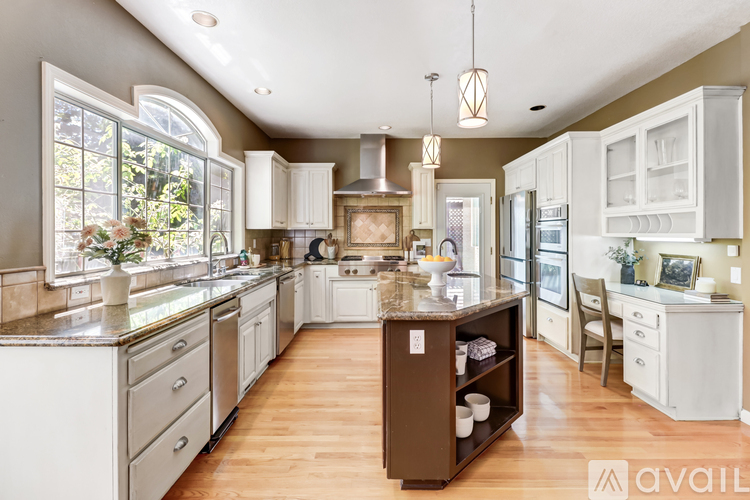A kitchen with white cabinets and a brown island.