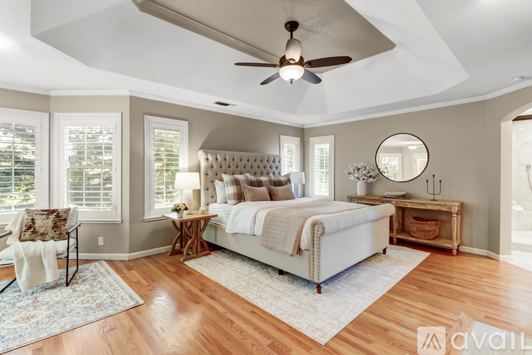 A bedroom with a large bed, a ceiling fan, and a window with blinds.