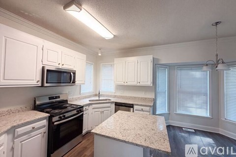 A kitchen with white cabinets and granite countertops.