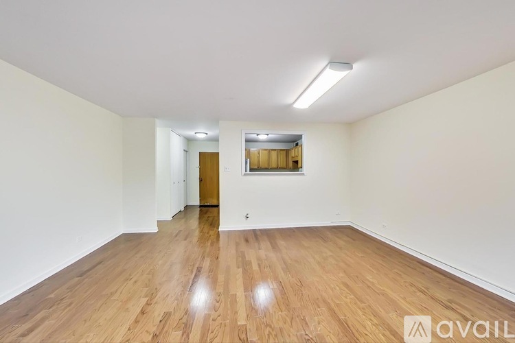 A spacious room with wooden flooring and white walls.
