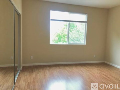 A room with a wooden floor and a window letting in sunlight.