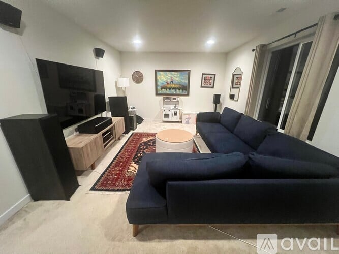 A living room with a black couch and a television.