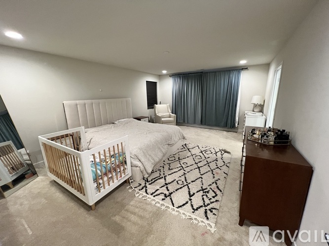 A well-lit bedroom with a white bed and a wooden crib.