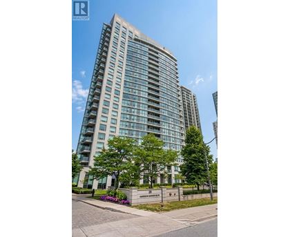 A tall residential building with a glass facade and a small garden in front.