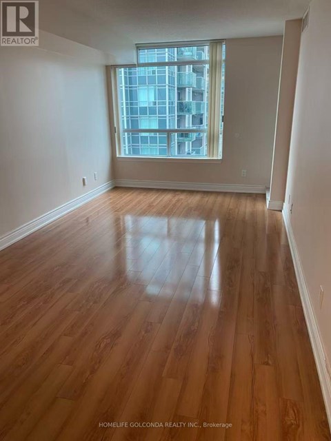 A room with wooden flooring and a large window.