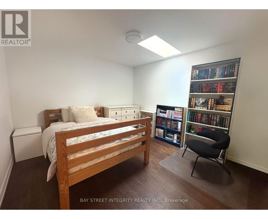 A bedroom with a bed, chair, and bookshelf.