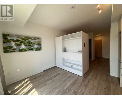 A white room with a painting of a pond and a white cabinet.