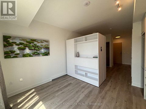 A white room with a painting of a pond and a white cabinet.