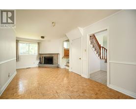 A spacious living room with a fireplace and a staircase.