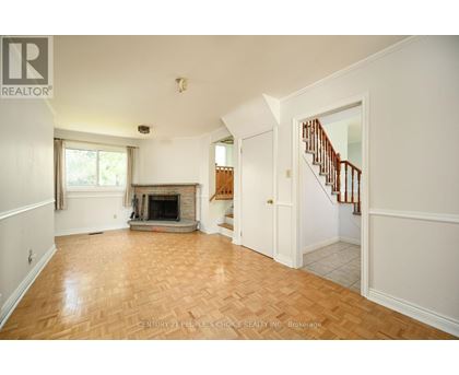 A spacious living room with a fireplace and a staircase.