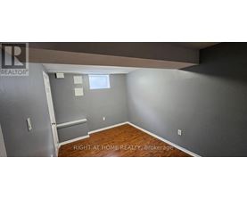 A room with a wooden floor and a wall with a window.