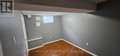 A room with a wooden floor and a wall with a window.