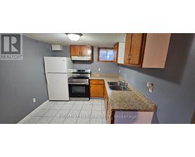 A kitchen with a white refrigerator, brown cabinets, and a granite countertop.