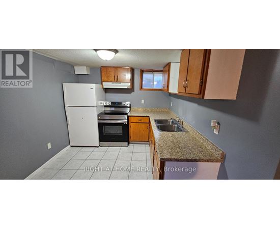 A kitchen with a white refrigerator, brown cabinets, and a granite countertop.