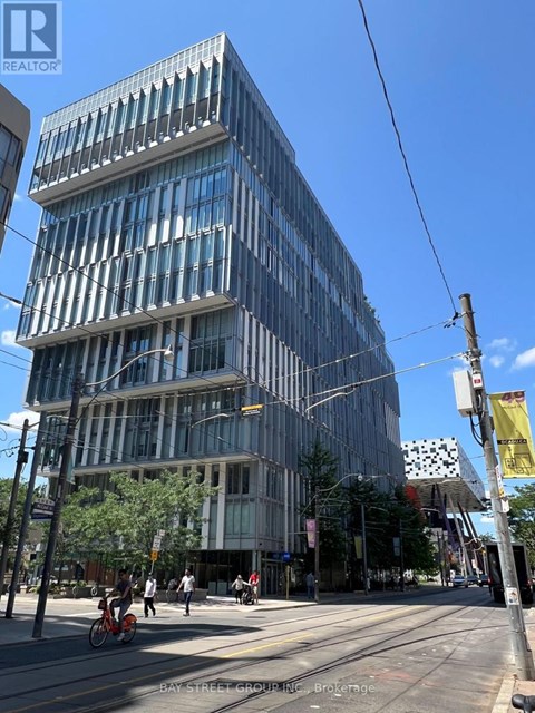 A modern glass building with a street in front of it.