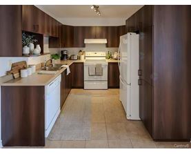 A kitchen with brown cabinets and white appliances.