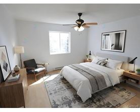 A bedroom with a large bed, a ceiling fan, and a chair.