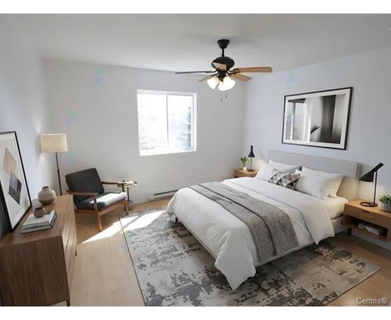 A bedroom with a large bed, a ceiling fan, and a chair.