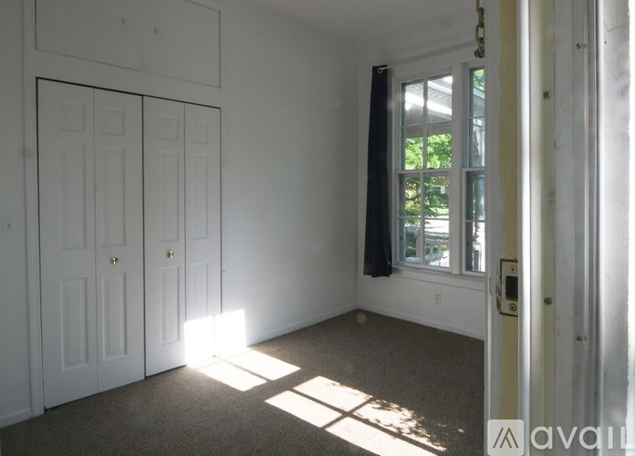 A room with two doors and a window letting in sunlight.
