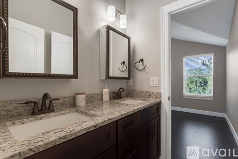 A bathroom with a marble countertop and a large mirror above the sink.