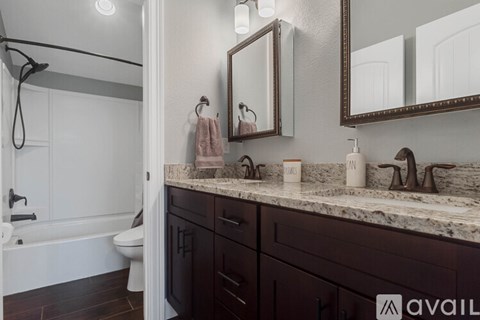 A bathroom with a marble countertop and dark wood cabinets.