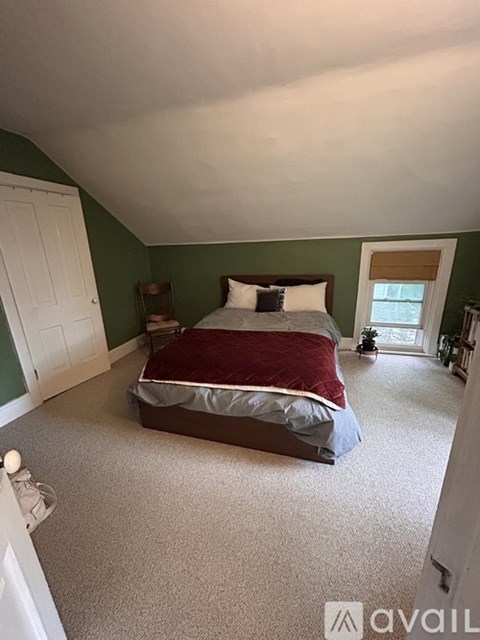A bedroom with a bed, carpet, and a window.