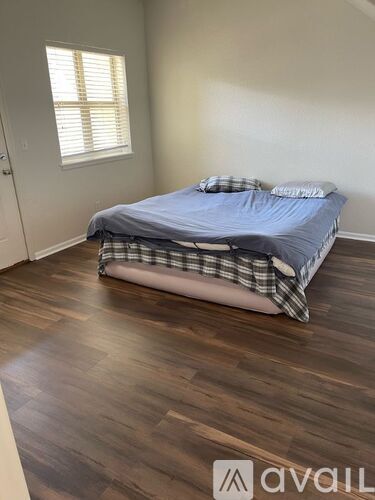 A bedroom with a bed and wooden flooring.