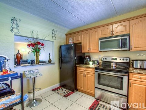 A kitchen with wooden cabinets and a black refrigerator.