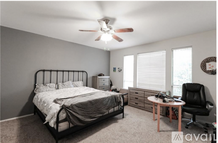 A bedroom with a bed, chair, and ceiling fan.