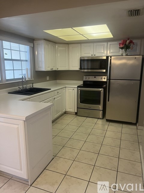 A kitchen with white cabinets and a refrigerator.