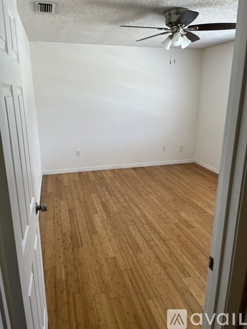 A room with a ceiling fan and wooden flooring.