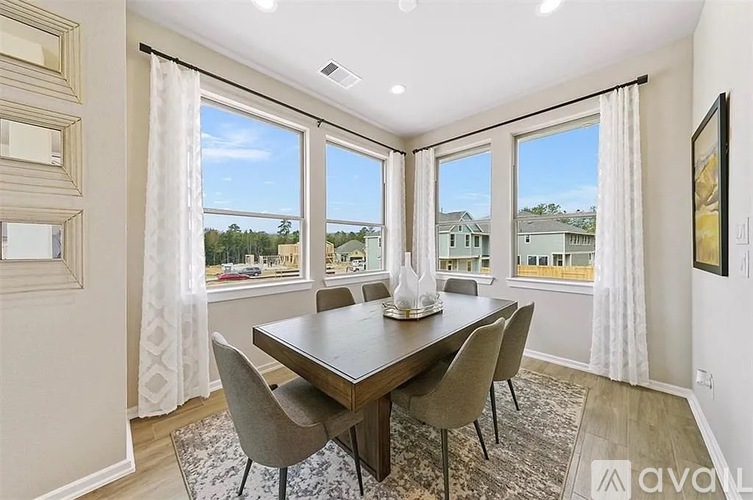 A dining room with a table and chairs and a view of the outside.