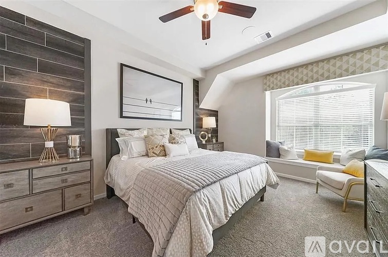 A bedroom with a large bed, a ceiling fan, and a window with blinds.