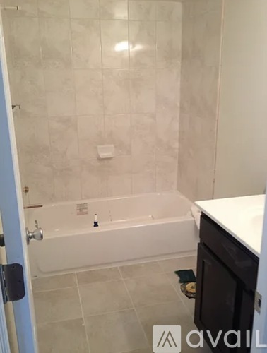A bathroom with a white tub and tiled walls.