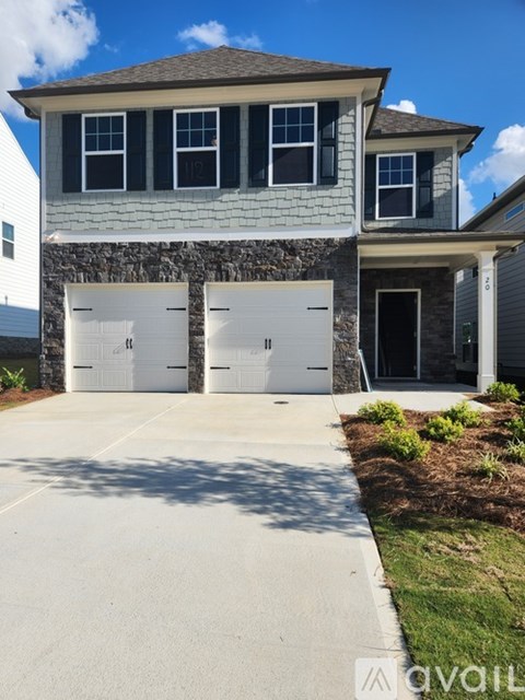 A house with a stone wall and two garage doors.