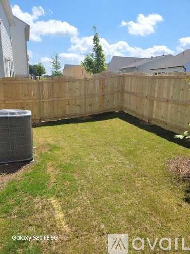 A backyard with a wooden fence and a grassy area.