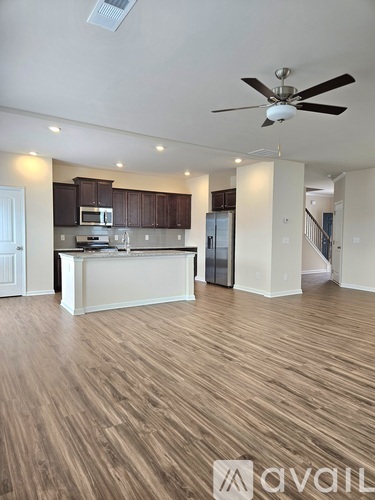 A spacious kitchen with wooden floors and a ceiling fan.